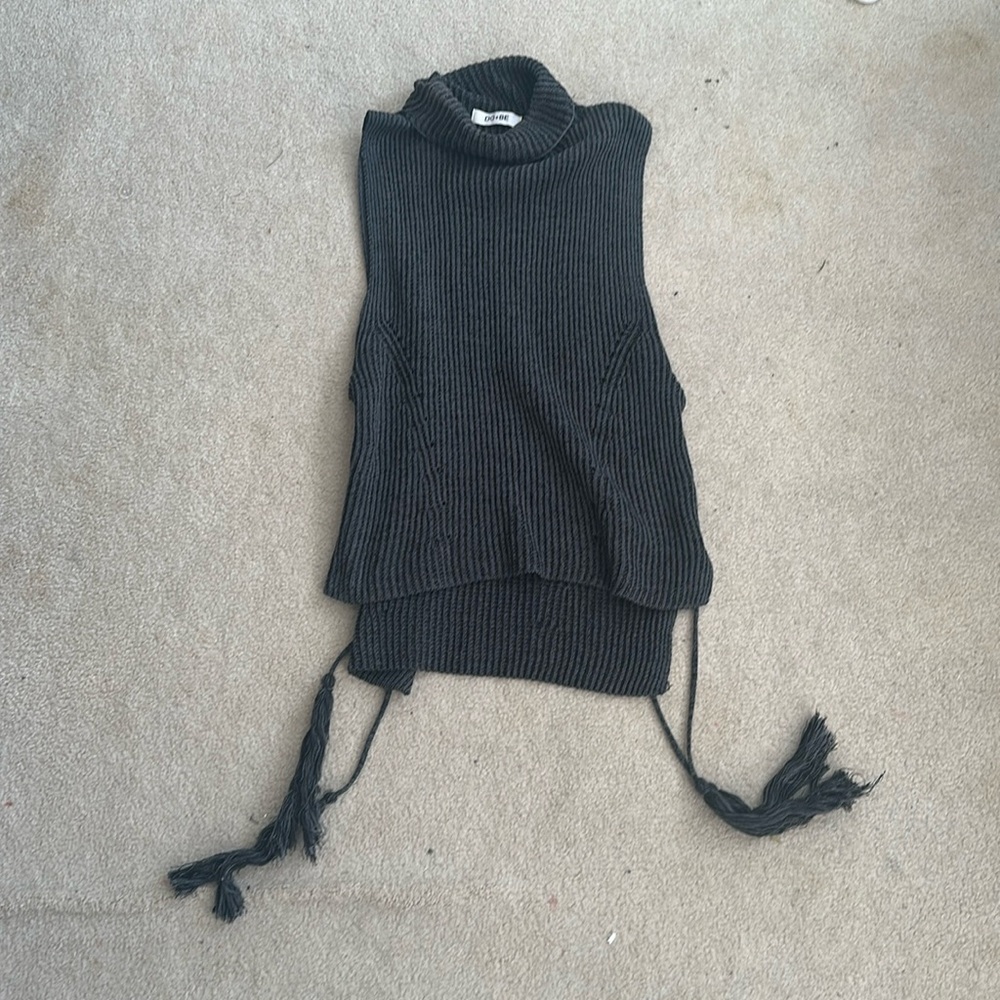 Sleevelesss turtleneck sweater with criss cross details and tassels